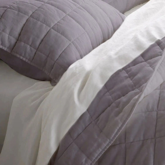 Gray quilted comforter on a bed with pillows