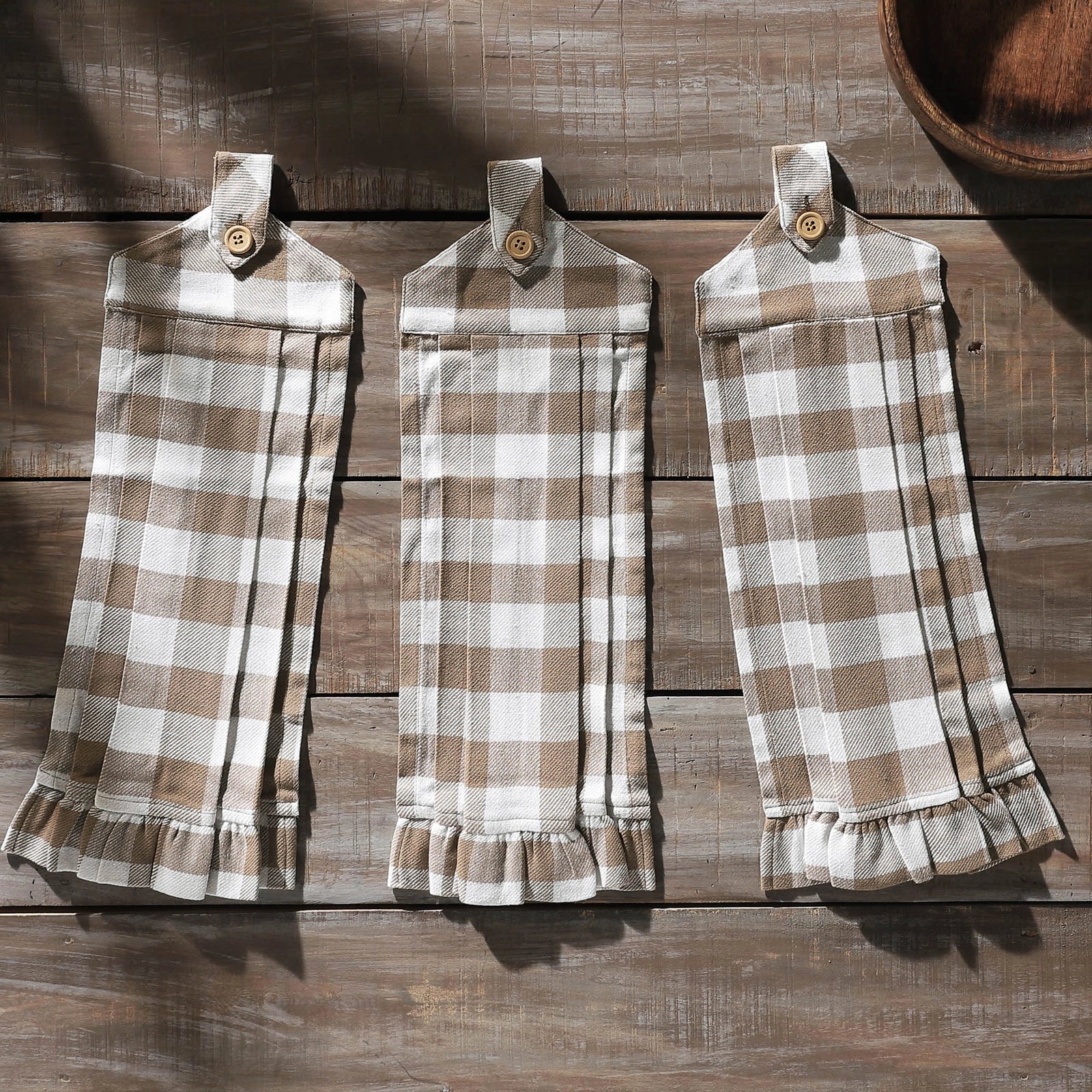 Three plaid aprons hanging on a wooden surface