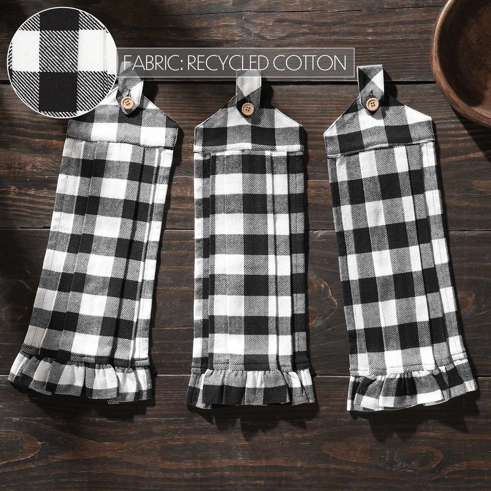 Three black and white checkered towels hanging on a wooden surface with a close-up of fabric texture above.