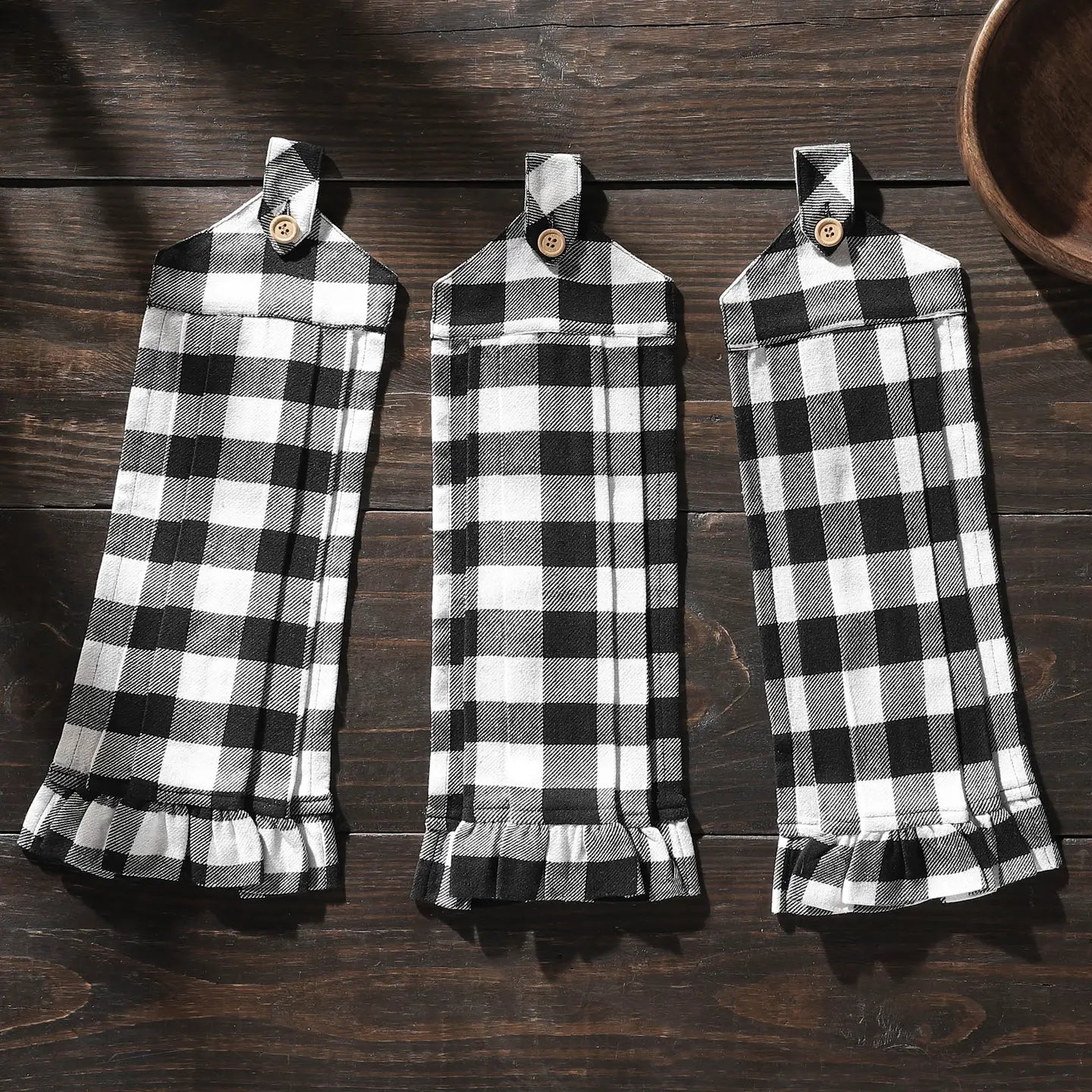 Three black and white checkered towels hanging on a wooden surface.