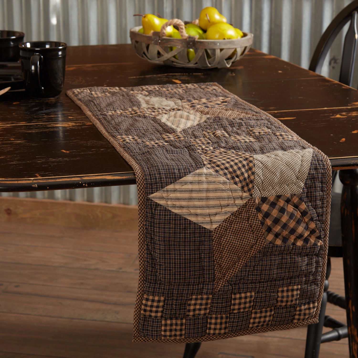 Patchwork table runner on a wooden table with a bowl of lemons in the background.