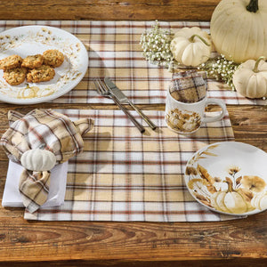 Thanksgiving table setting with plaid placemats, pumpkins, and fall-themed plates.
