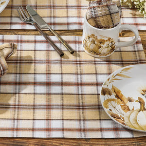 Plaid tablecloth with a cup, plate, and cutlery on a wooden surface