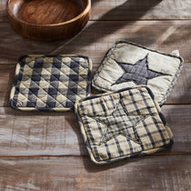 Three quilted pot holders with star designs on a wooden surface