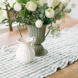 Green vase with white flowers on a checkered tablecloth