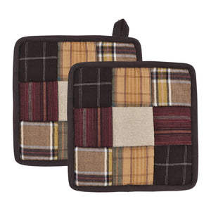 Two square patchwork potholders with a rustic plaid and solid fabric design in brown, beige, and red tones, shown on a plain white background.